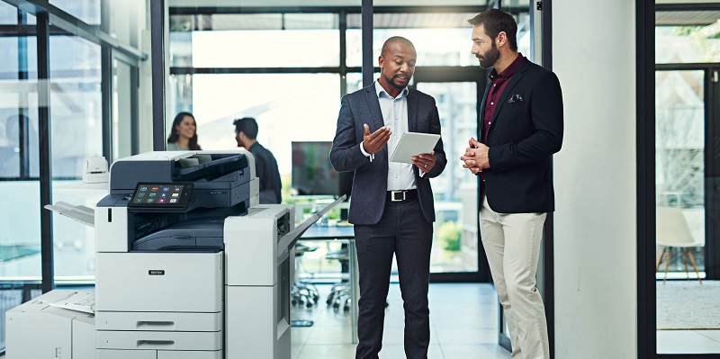 Two men standing next to a Xerox AltaLink multifunction printer