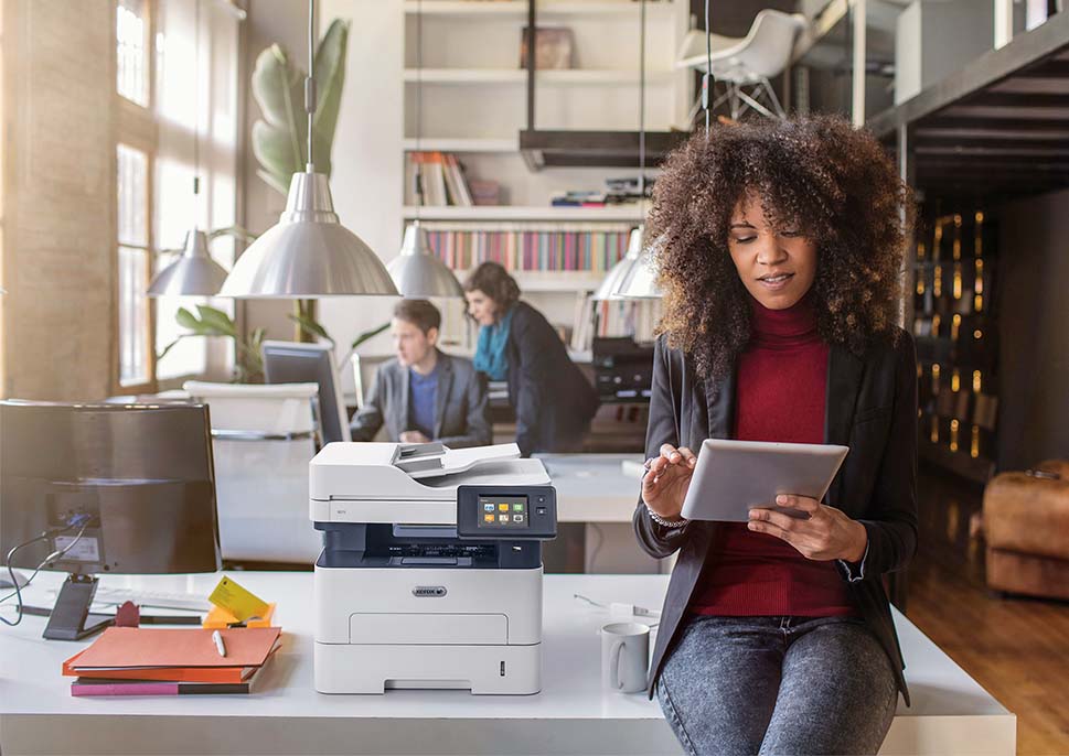 Woman in office next to a Xerox B215 printer