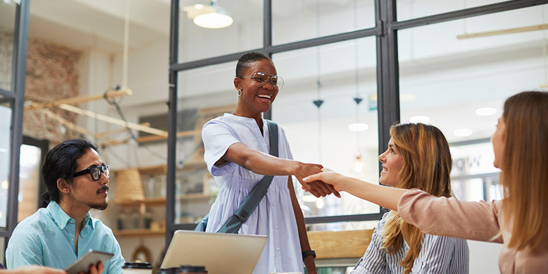 Co-workers hand shaking over table.