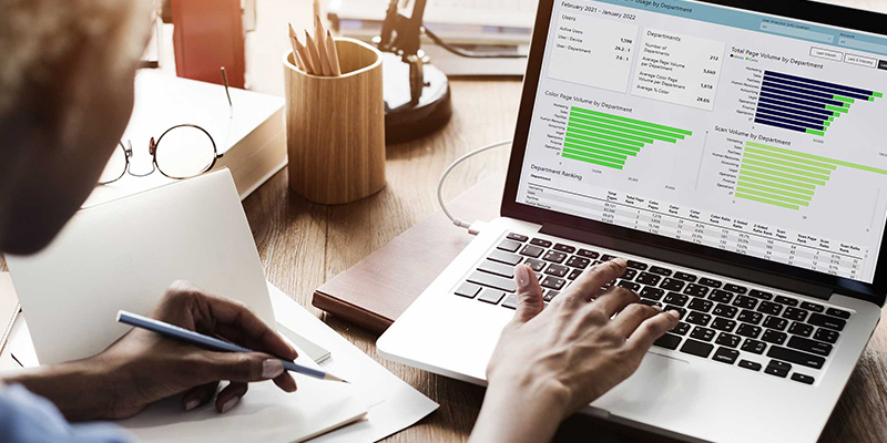 Person sitting at a computer screen looking at charts.
