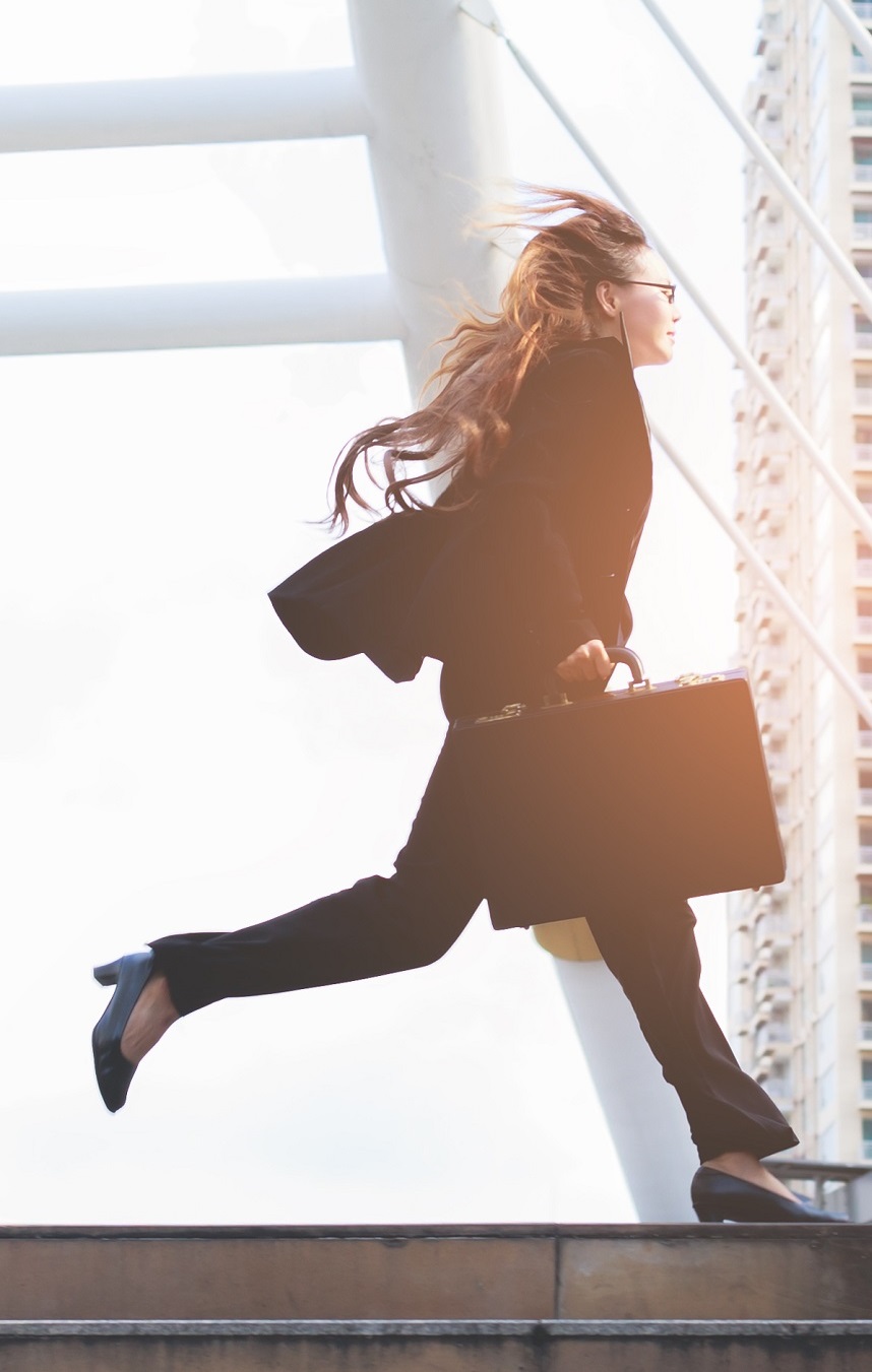 Woman in business suit running, carrying a briefcase