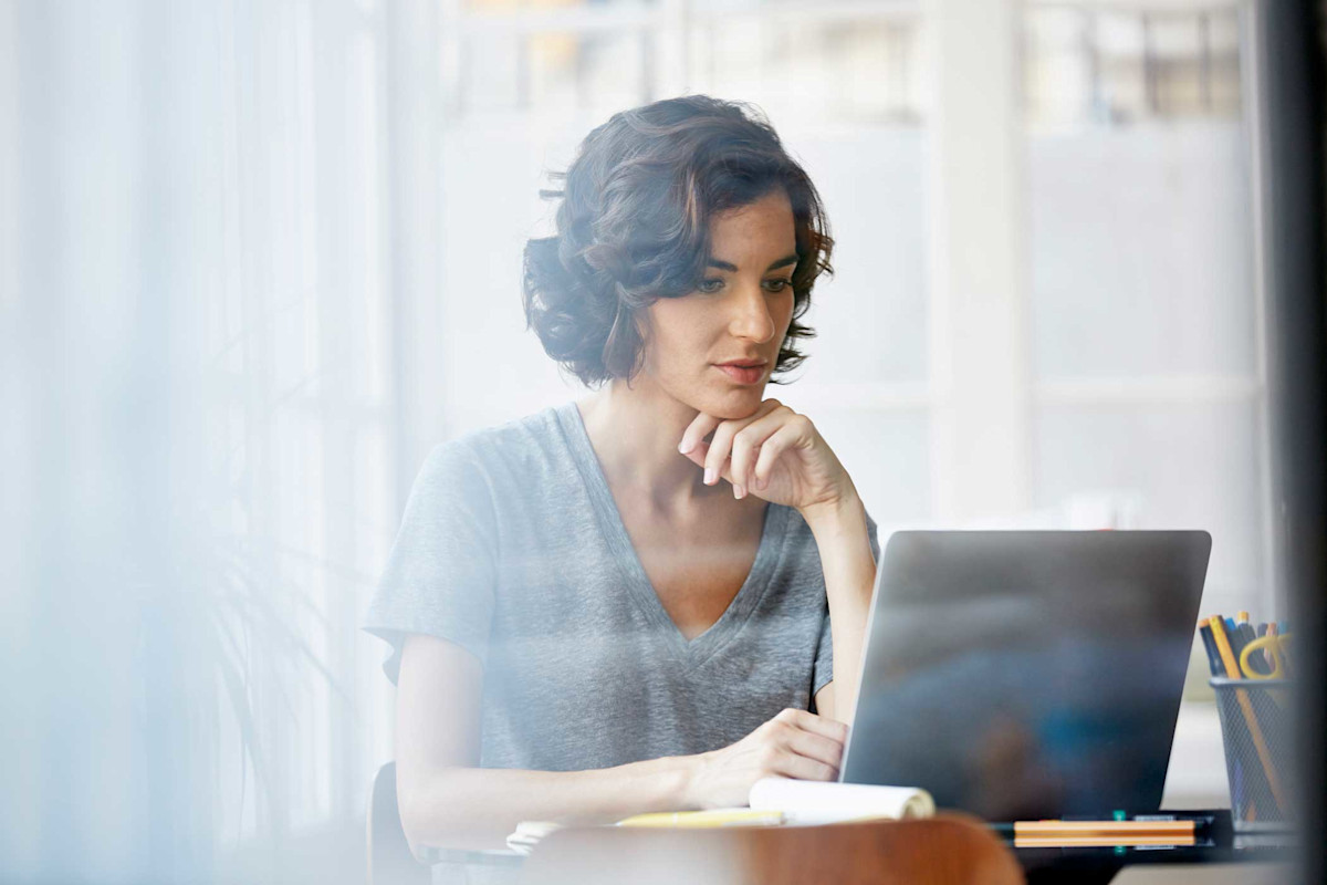 View through a window of a woman working on a laptop
