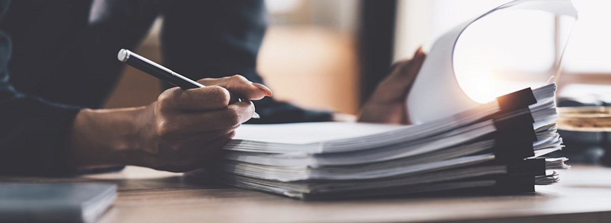 Writing on a stack of papers organized with binder clips